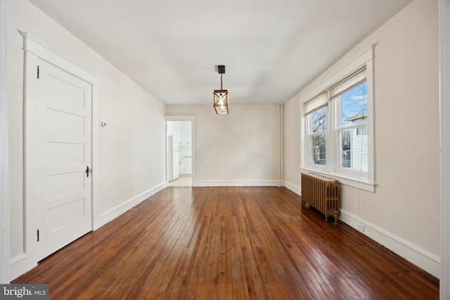 spare room featuring dark wood-type flooring and radiator