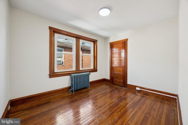 unfurnished room with radiator and dark wood-type flooring