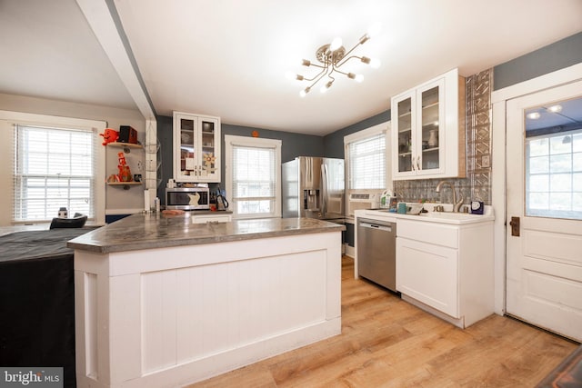 kitchen featuring appliances with stainless steel finishes, sink, white cabinets, decorative backsplash, and light hardwood / wood-style flooring