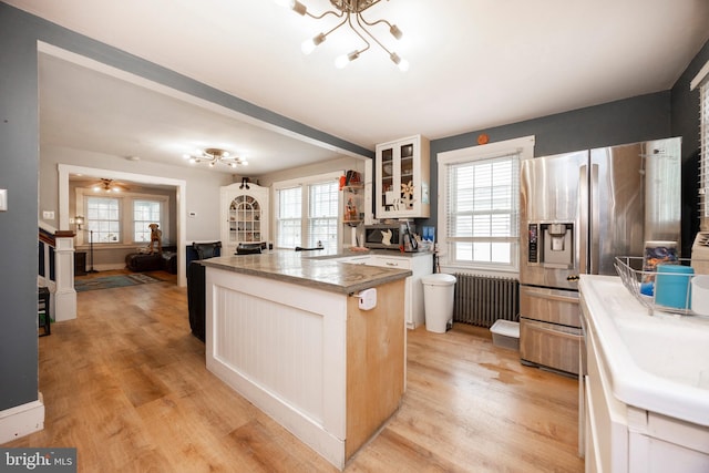 kitchen with white cabinetry, appliances with stainless steel finishes, light hardwood / wood-style floors, and radiator heating unit