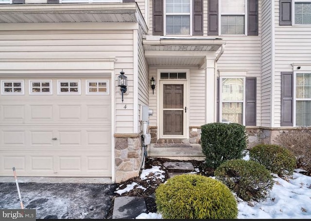 snow covered property entrance featuring a garage