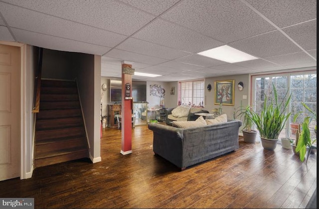 living room with dark hardwood / wood-style floors and a drop ceiling