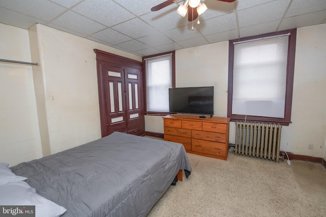 bedroom with ceiling fan, a paneled ceiling, and radiator heating unit