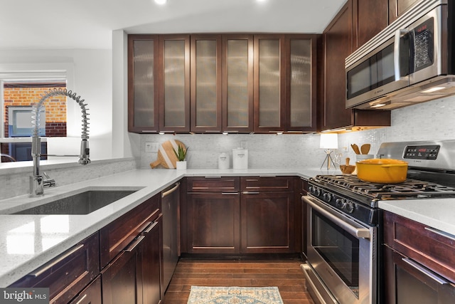 kitchen featuring appliances with stainless steel finishes, sink, backsplash, dark hardwood / wood-style floors, and light stone counters