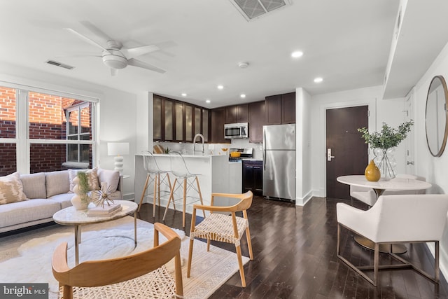 living room featuring ceiling fan, sink, and dark hardwood / wood-style floors