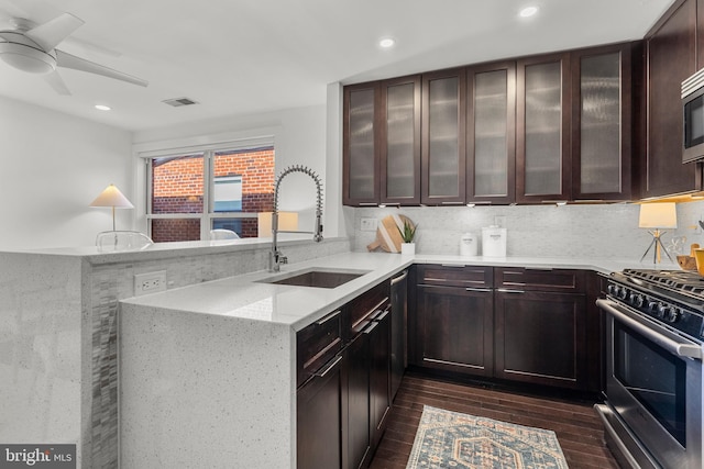 kitchen with light stone counters, sink, kitchen peninsula, and stainless steel appliances