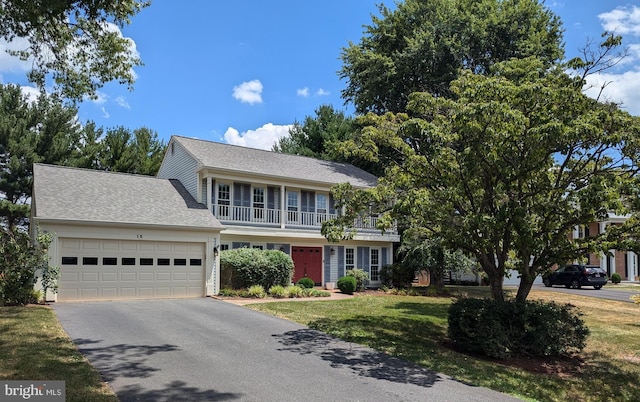 view of front of house featuring a balcony, a garage, and a front lawn