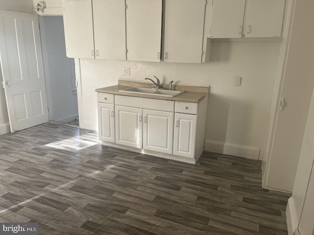 kitchen with dark hardwood / wood-style flooring, white cabinets, and sink