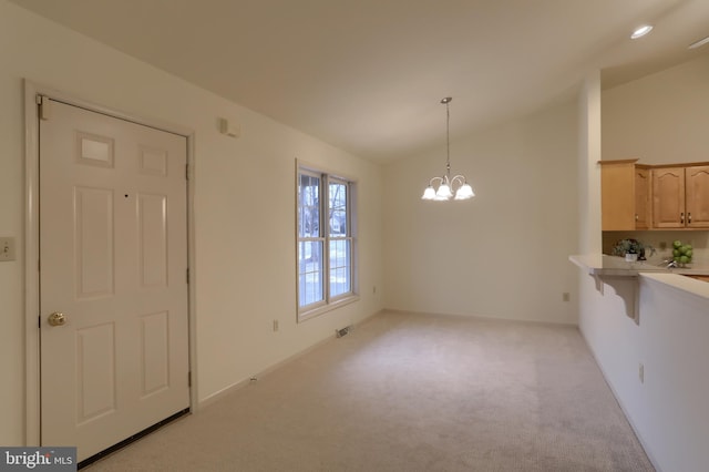 unfurnished dining area featuring light carpet, an inviting chandelier, and lofted ceiling