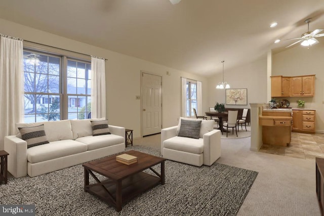 carpeted living room featuring lofted ceiling, a healthy amount of sunlight, and ceiling fan with notable chandelier