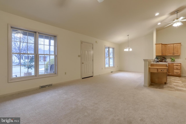 carpeted living room featuring vaulted ceiling, ceiling fan with notable chandelier, and plenty of natural light