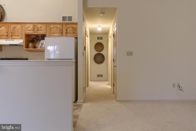 kitchen with light brown cabinetry, light colored carpet, and white refrigerator