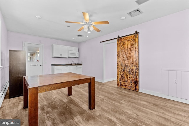 kitchen featuring white cabinetry, sink, light wood-type flooring, ceiling fan, and a barn door