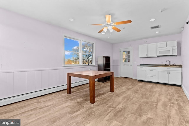 kitchen with ceiling fan, a baseboard radiator, white cabinetry, and light wood-type flooring