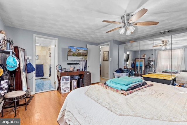 bedroom with a textured ceiling, ceiling fan, light hardwood / wood-style floors, and ensuite bath