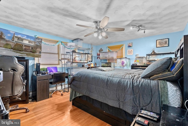 bedroom with a textured ceiling, ceiling fan, and hardwood / wood-style flooring