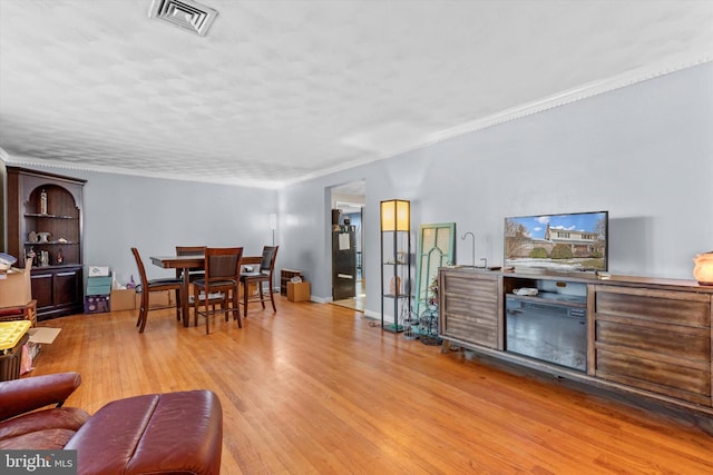 living room featuring light wood-type flooring and ornamental molding