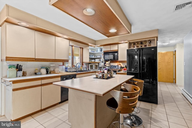 kitchen with light tile patterned floors, a breakfast bar area, a kitchen island, black appliances, and sink