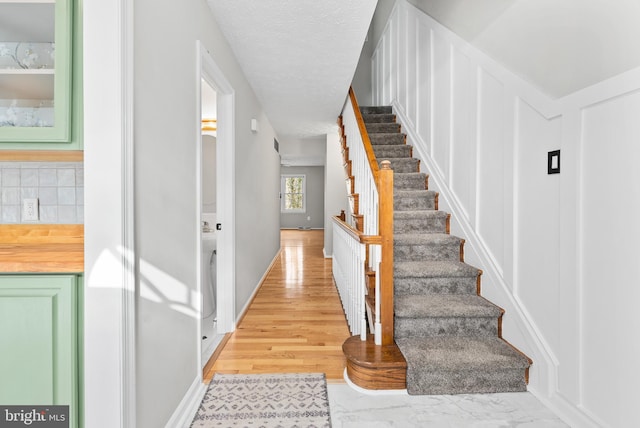 staircase with hardwood / wood-style floors and a textured ceiling