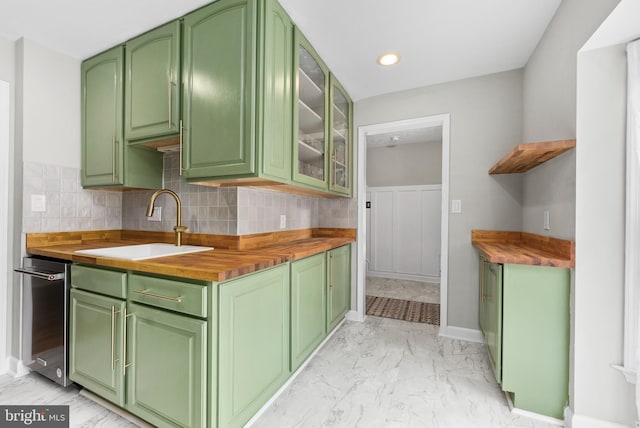 kitchen with butcher block counters, sink, decorative backsplash, and green cabinets