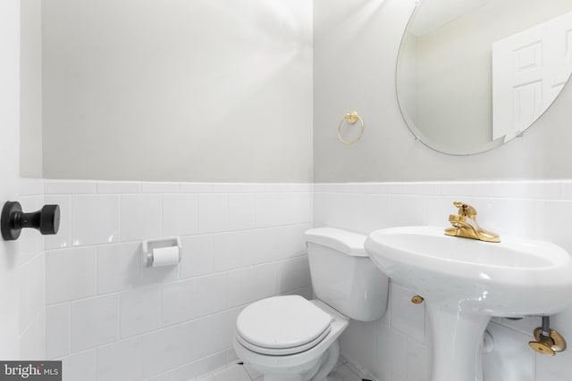 bathroom with tile walls and toilet