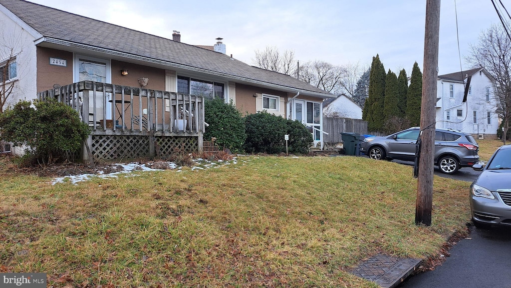 view of front facade featuring a front lawn and a wooden deck