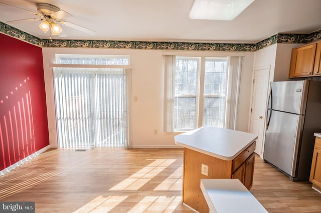 kitchen featuring ceiling fan, a kitchen island, stainless steel fridge, and light wood-type flooring