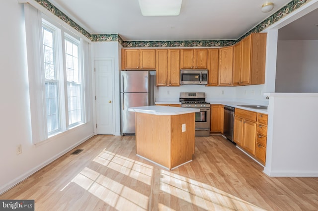 kitchen with stainless steel appliances, a healthy amount of sunlight, a center island, and sink