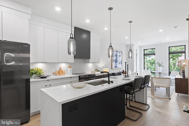 kitchen with white cabinets, fridge, and an island with sink