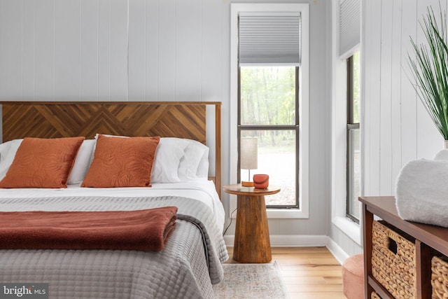 bedroom with light hardwood / wood-style floors and wooden walls