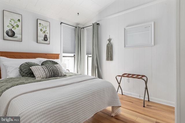 bedroom featuring vaulted ceiling, ornamental molding, and wood-type flooring