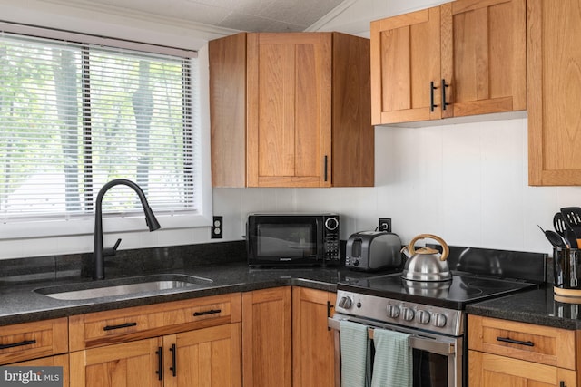 kitchen featuring electric stove, crown molding, sink, and dark stone countertops