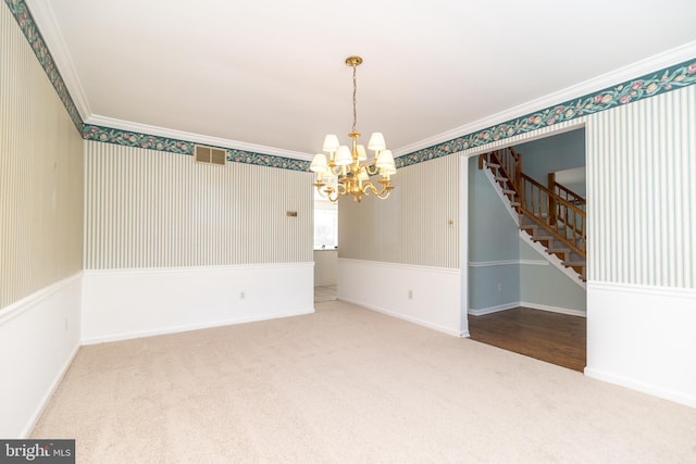 carpeted spare room featuring crown molding and an inviting chandelier