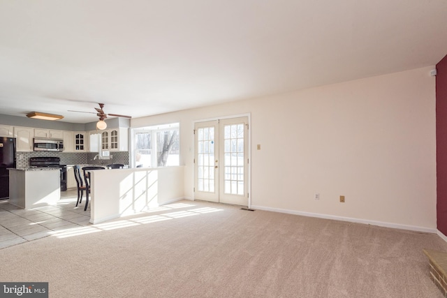 unfurnished living room featuring light carpet, ceiling fan, and french doors