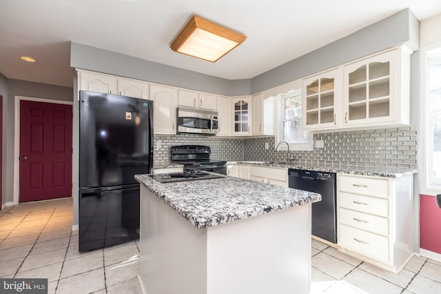 kitchen with light stone countertops, a center island, decorative backsplash, and black appliances