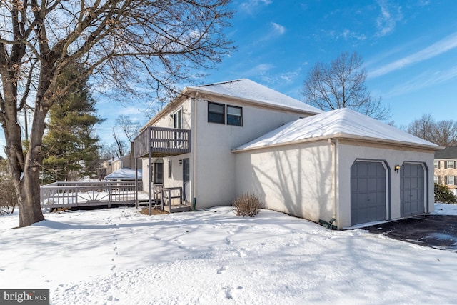 view of snow covered exterior with a garage, a wooden deck, and a balcony