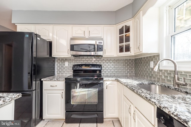 kitchen featuring sink, black appliances, light stone countertops, and light tile patterned flooring