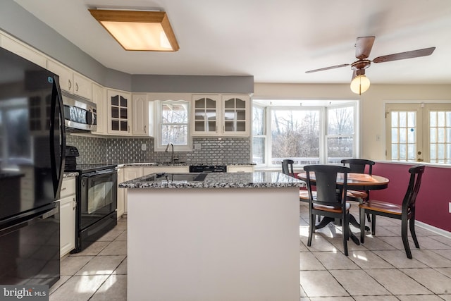 kitchen featuring sink, a center island, light tile patterned floors, and black appliances