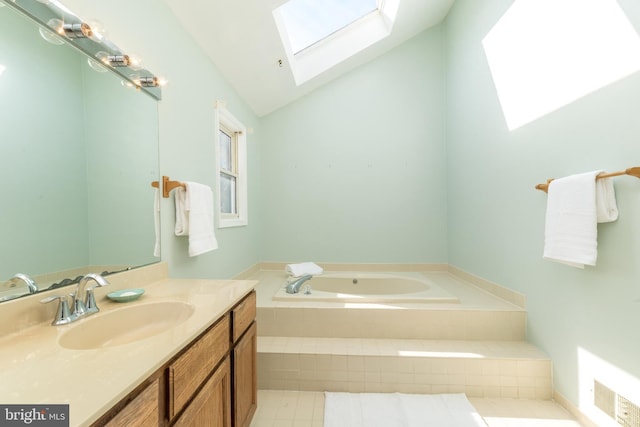 bathroom featuring vanity, lofted ceiling with skylight, tile patterned flooring, and tiled tub