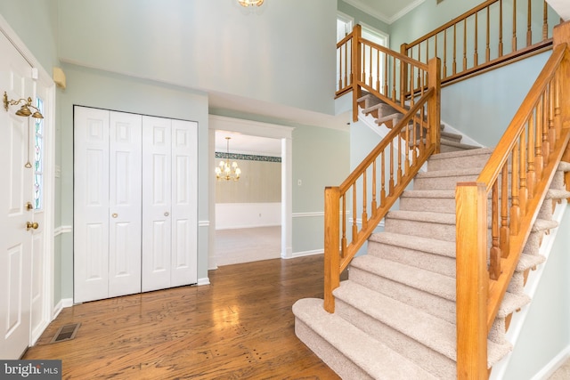 stairs with ornamental molding, hardwood / wood-style floors, and a chandelier