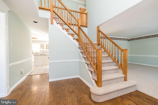 staircase with hardwood / wood-style flooring and ornamental molding