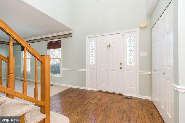 foyer with ornamental molding, a healthy amount of sunlight, and hardwood / wood-style floors