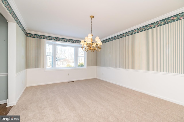 spare room with a notable chandelier, ornamental molding, and carpet