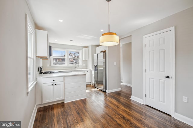 kitchen featuring stainless steel refrigerator with ice dispenser, light countertops, dark wood-type flooring, white cabinets, and a sink