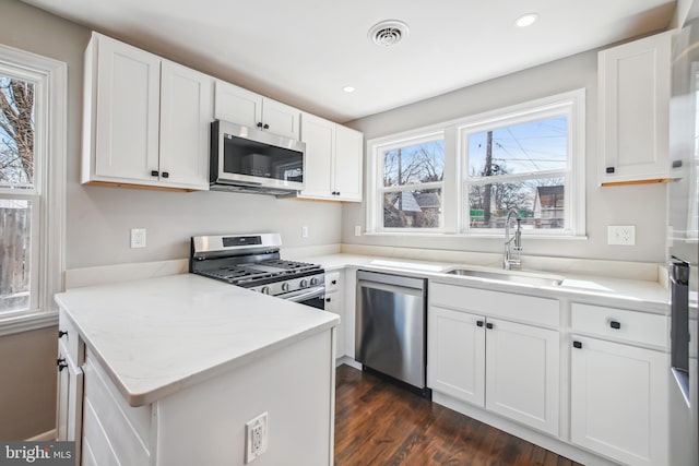 kitchen with appliances with stainless steel finishes, white cabinets, visible vents, and a sink