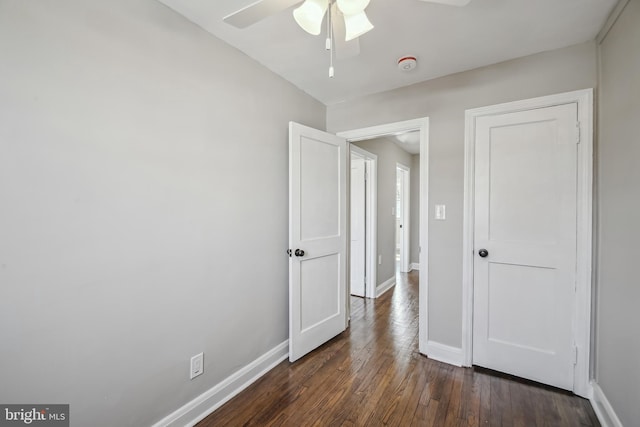 unfurnished bedroom featuring dark wood-style floors, baseboards, and a ceiling fan