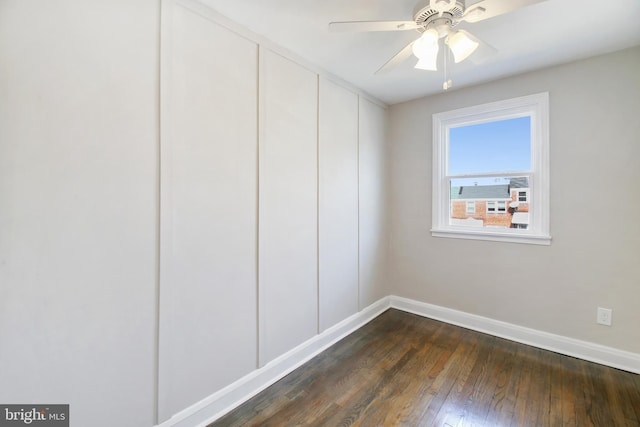 unfurnished room with baseboards, dark wood finished floors, and a ceiling fan