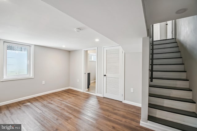 below grade area featuring recessed lighting, stairway, baseboards, and wood finished floors