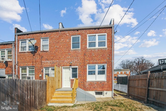 rear view of house with fence and brick siding