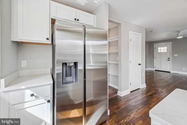 kitchen featuring stainless steel fridge, baseboards, dark wood-type flooring, light stone countertops, and white cabinetry